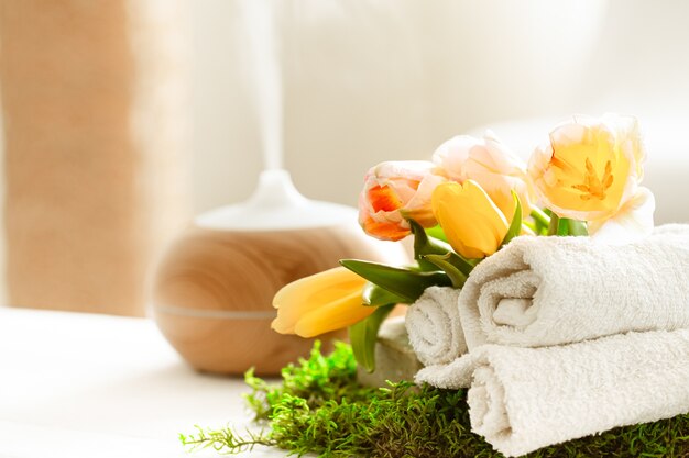 タオル付きのモダンなオイルディフューザーの香りが漂う春のスパ静物。