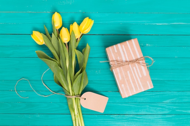 Spring tulip flowers; and gift box on green wooden table