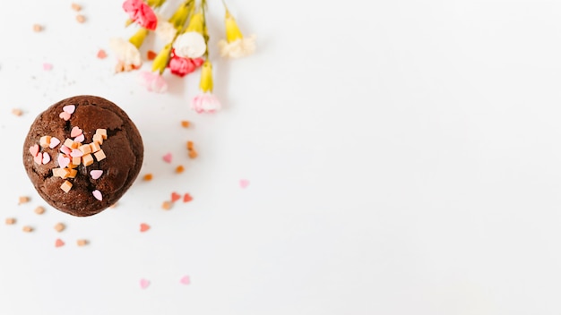 흰색 배경에 꽃과 초콜릿 컵 케이크에 카라멜 사탕을 뿌린다