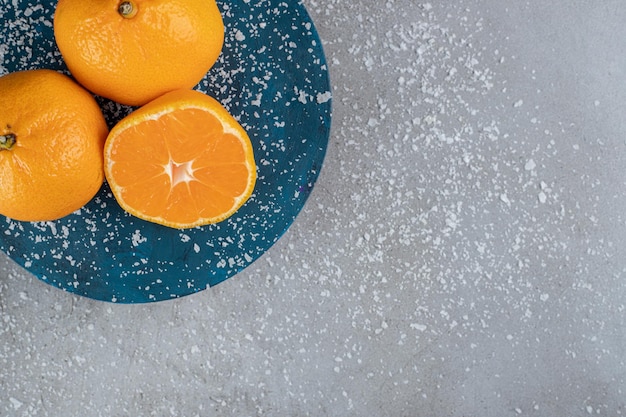 Foto gratuita polvere di cocco spruzzata e un piatto di arance sul tavolo di marmo.