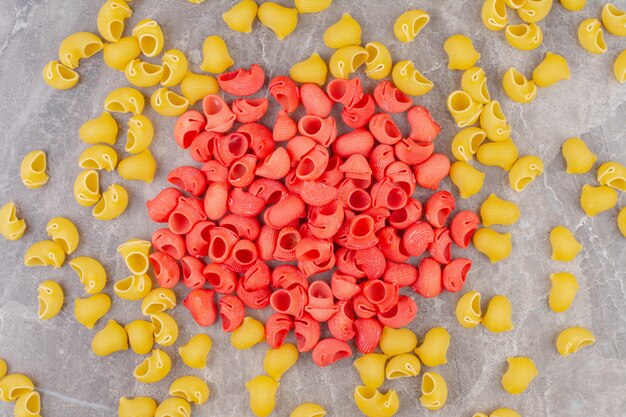 Free photo sprinkled red and yellow pipe pasta, on the marble.