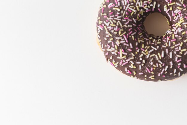 Sprinkles on chocolate donuts over white backdrop