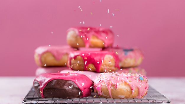 Free photo sprinkles falling on glazed donuts