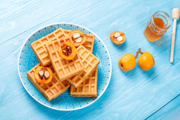 Square belgian waffles with loquat fruits and honey.