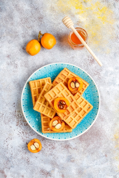 Free photo square belgian waffles with loquat fruits and honey