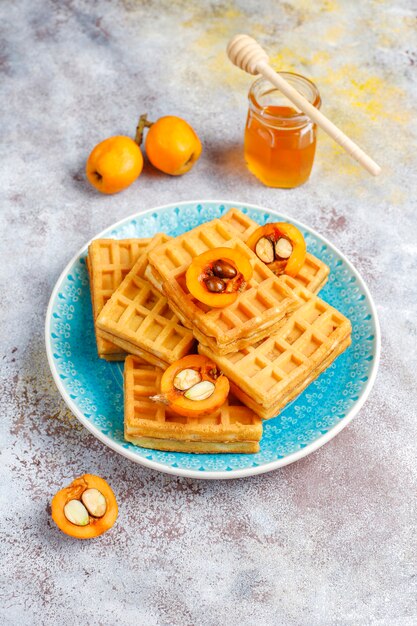 Square belgian waffles with loquat fruits and honey.