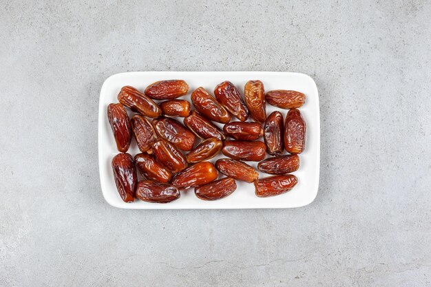 Square plate full of dates on marble surface