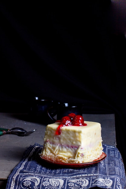 Square portioned cherry cake covered in white chocolate topped with cherry and syrup