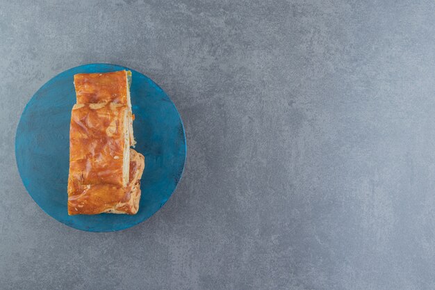 Square shaped stuffed pastries on blue board. 