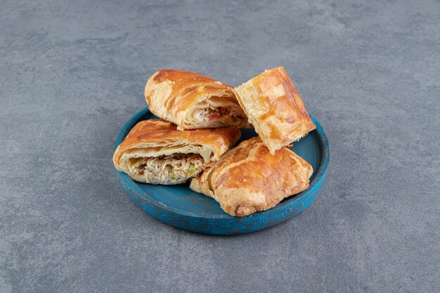 Square shaped stuffed pastries on blue plate.