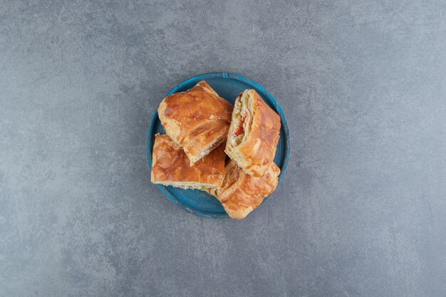 Square shaped stuffed pastries on blue plate.