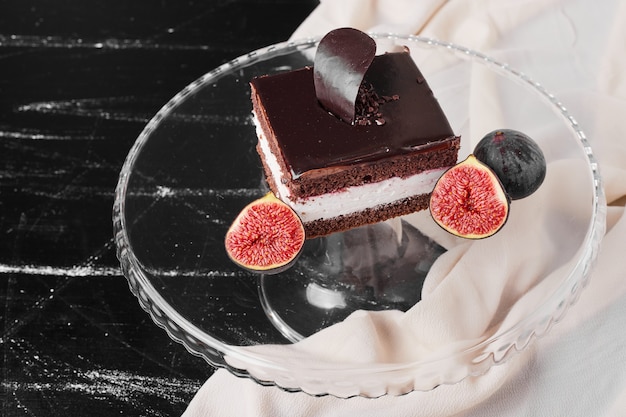 A square slice of chocolate cheesecake on a glass platter.