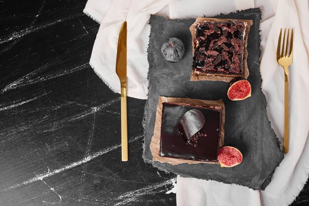 A square slice of chocolate cheesecake on a stone board.