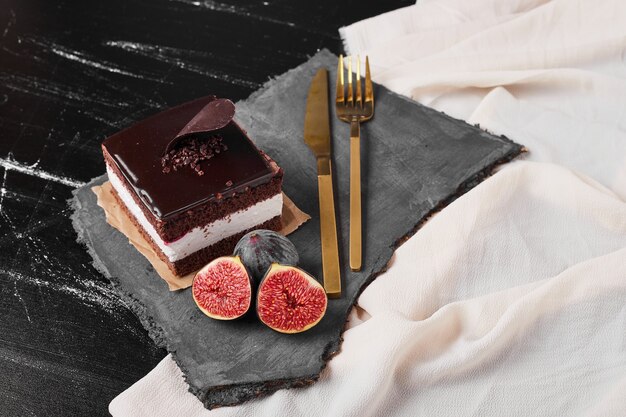 A square slice of chocolate cheesecake on a stone platter.