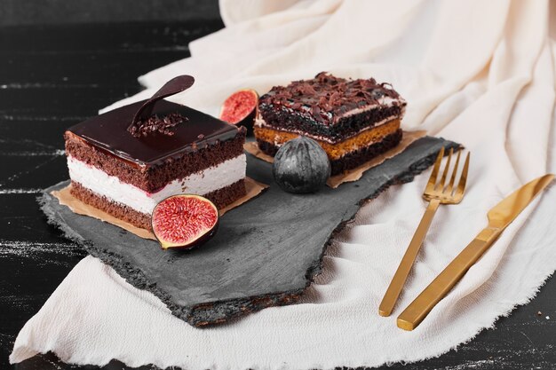 A square slice of chocolate cheesecake on a stone platter.