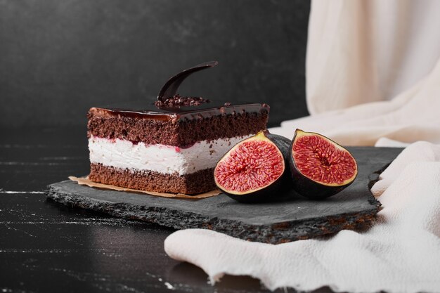 A square slice of chocolate cheesecake on a stone platter.