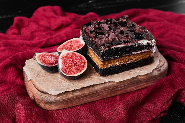 A square slice of chocolate cheesecake on a wooden board.