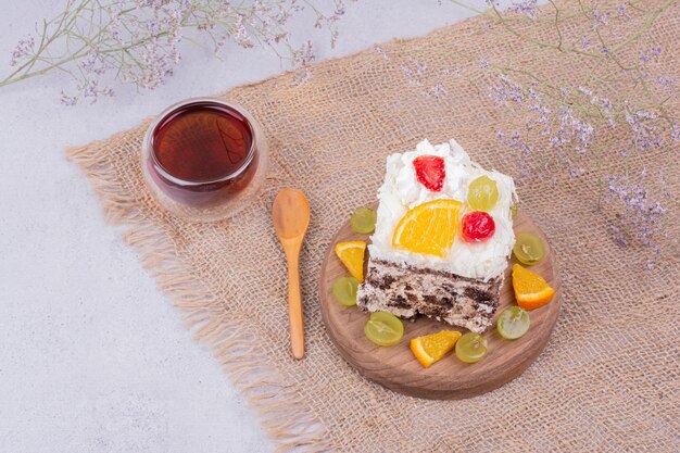 A square slice of fruit cake with a glass of tea.