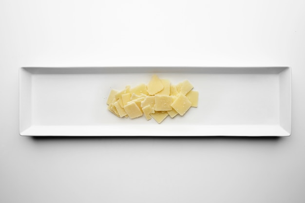 Square slices of parmesan isolated on white plate in center