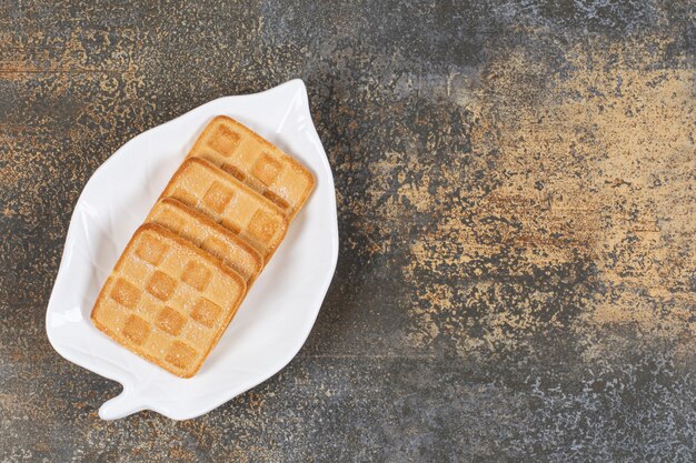 Квадратные сладкие крекеры на тарелке в форме листа.