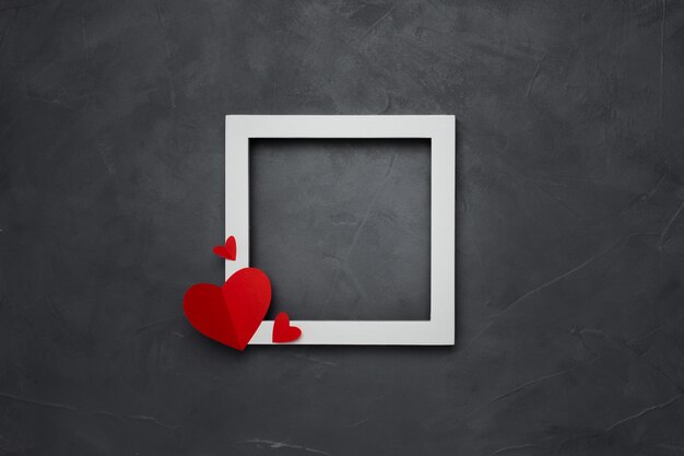 Square white empty frame with hearts on gray textured background with copyspace