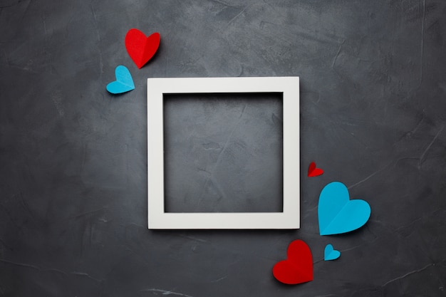 Square white empty frame with hearts on gray textured background with copyspace