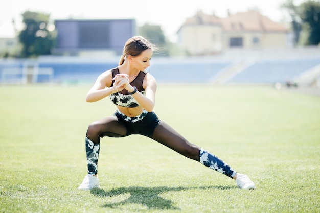 Free photo squatting. young beauty girl do exercises at the stadium