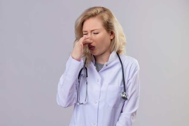 Squeamish doctor young girl wearing stethoscope in medical gown closed nose on white background