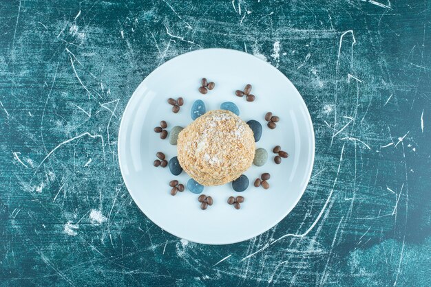 Squirrel cake on a platter with candy rocks and coffee beans on blue.