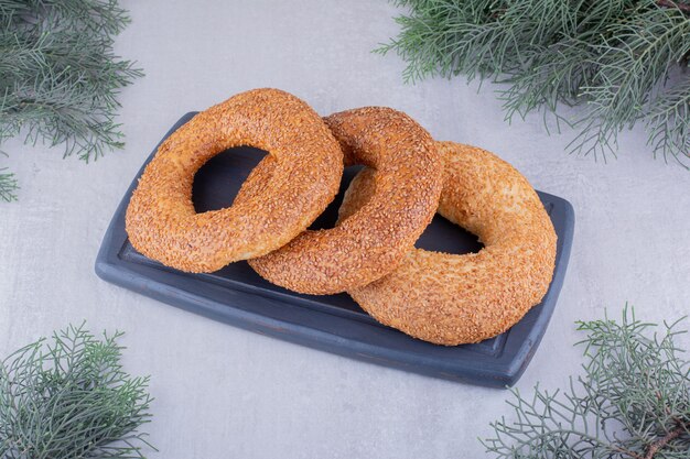 Stack of bagels on a navy board on white background.
