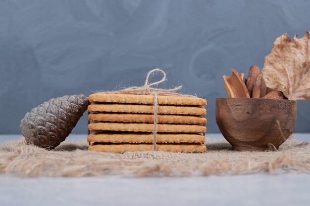 Stack of biscuits and cinnamons sticks on burlap. High quality photo