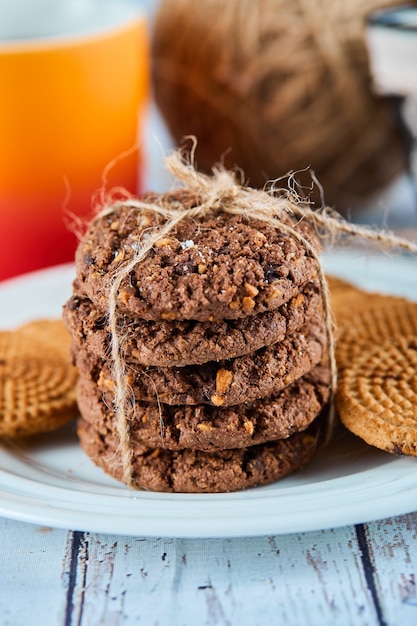 Stack of biscuits in plate and basket and a cup on blue table.