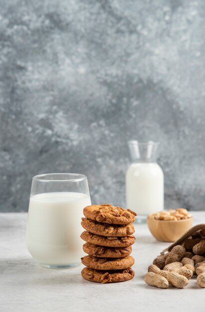 Stack of biscuits with honey, milk and peanuts on marble table. 