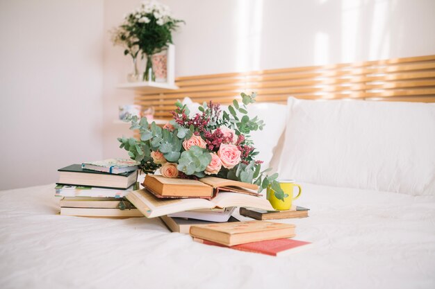 Stack of books and bouquet on bed