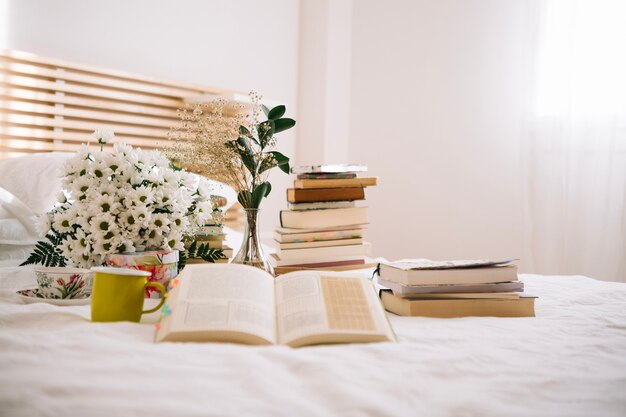 Stack of books and flowers on bed
