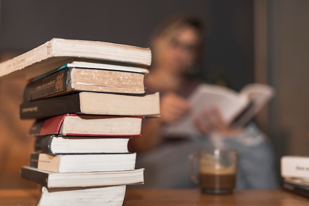 La pila di libri si avvicina a leggere donna e caffè