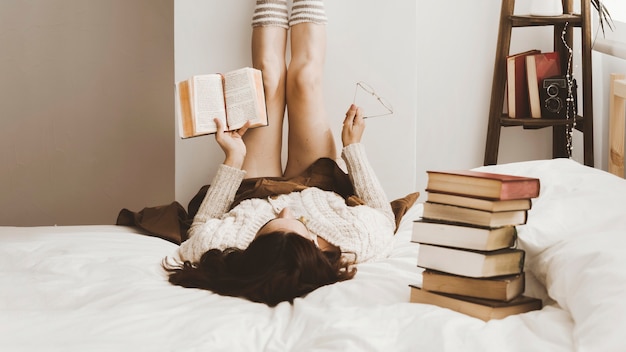 Stack of books near reading woman