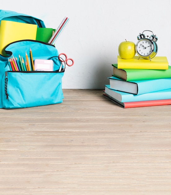 Stack of books and school backpack on floor