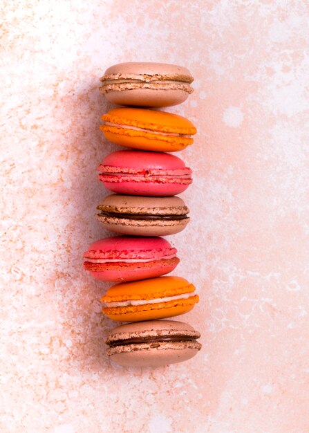 Stack of brown; orange and pink macaroons on textured weathered backdrop