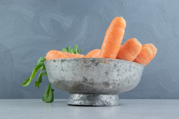 A stack of carrots in the bowl , on the marble background.