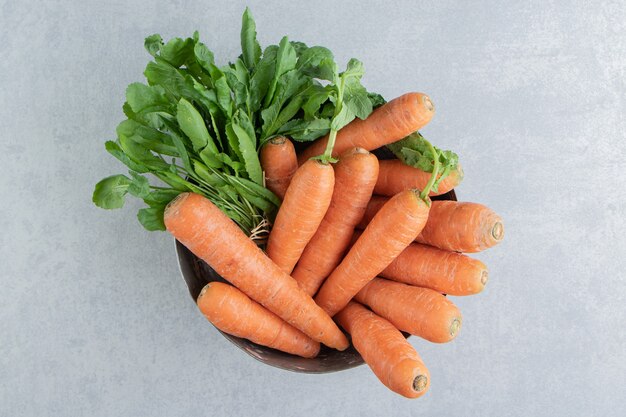 A stack of carrots in the bowl , on the marble.