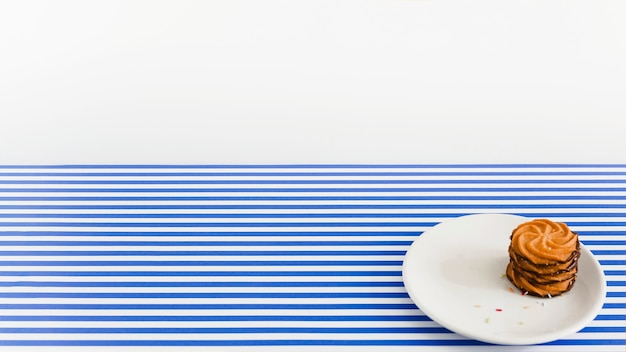 Stack of chocolate cookies on white plate over the stripes background