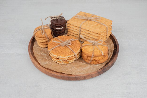 Stack of Christmas cookies tied with rope on wooden plate