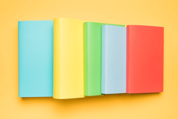 Stack of colorful blank books on yellow background 