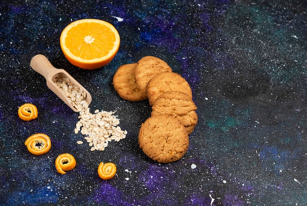 Foto gratuita pila di biscotti e farina d'avena con mezza arancia tagliata sulla superficie dello spazio.