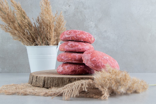 Stack of cookies on a board next to feather grass bundle on marble background.