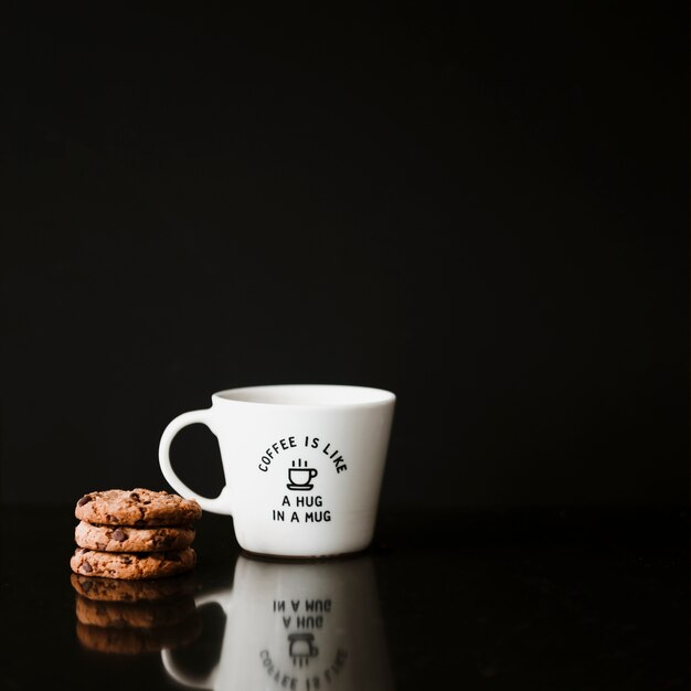 Stack of cookies and ceramic cup on black background