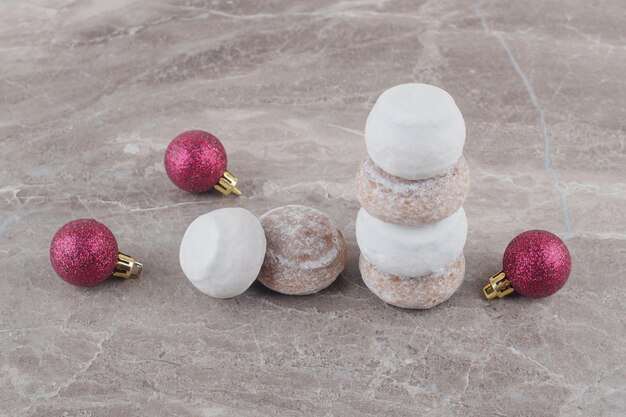 A stack of cookies and Christmas baubles bundled up on marble 