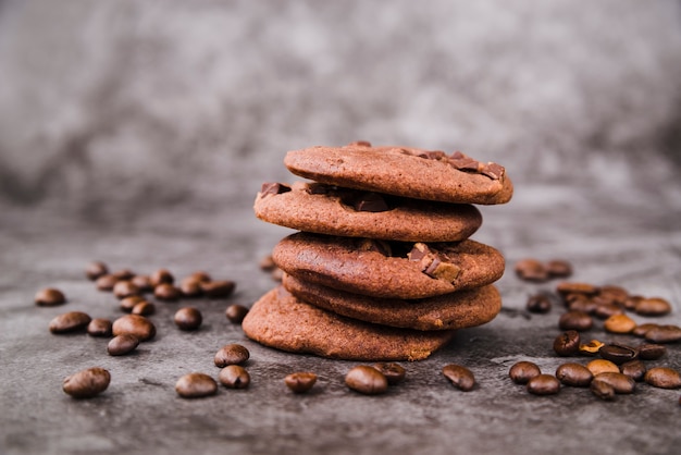 Stack of cookies and roasted coffee beans on grunge backdrop