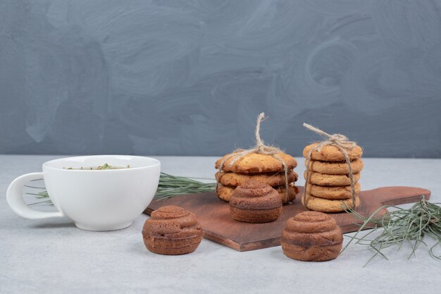 Stack of cookies tied with rope and cup of tea on gray background.